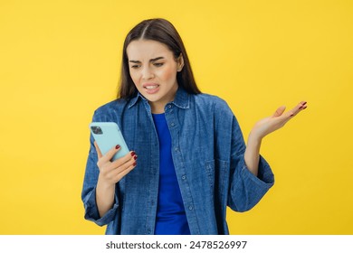 Annoyed angry young woman mad about spam message stuck phone looking at smartphone isolated on yellow studio background, furious teen girl having problem with cellphone irritated by broken mobile - Powered by Shutterstock