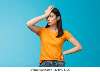 Annoyed arrogant asian girl punch forehead make facepalm sign, roll eyelids irritated pissed, cannot stand lame talks look disappointed ingorant, unwilling to listen, stand blue background