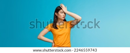 Annoyed arrogant asian girl punch forehead make facepalm sign, roll eyelids irritated pissed, cannot stand lame talks look disappointed ingorant, unwilling to listen, stand blue background.