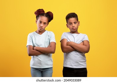 Annoyed Black Boy And Girl With Arms Crossed On Chests Looking At Camera On Yellow, African American Kids Brother And Sister Expressing Negative Emotions And Feelings, Do Not Like Something