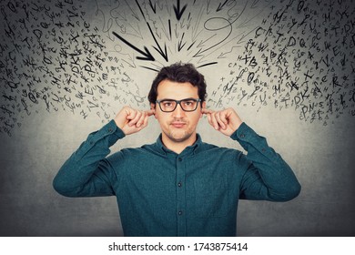 Annoyed businessman covers ears with fingers, looks displeased, refuses to listen, as multiple letters and words try to enter inside his head. Frustrated guy dissatisfied of high noise from outside. - Shutterstock ID 1743875414