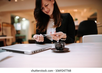 Annoyed Businesswoman Trying To Untangle Earphones.