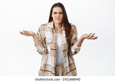 Annoyed And Confused Woman Cant Understand Wtf Happening, Shrugging Shoulders And Grimacing At Something Ridiculous And Stupid, Dont Know Nothing, Standing Careless Against White Background