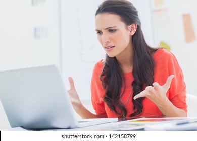Annoyed designer gesturing in front of her laptop in her office