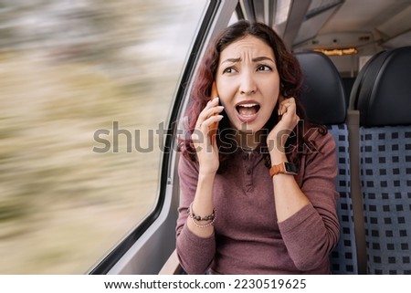 Annoyed girl is traveling on a train and because of the noise and a bad signal, she cannot hear the interlocutor. Poor cellular network coverage