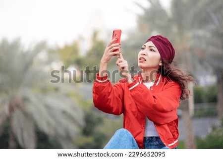 Annoyed girl unsuccessfully tries to catch a cellular signal or an unstable WiFi, holding her smartphone in her hands