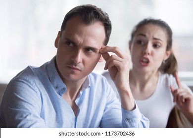 Annoyed husband tired of wife scolding or lecturing him, millennial couple having fight or disagreement at home, bothering woman press exhausted and nervous man. Breakup or separation concept