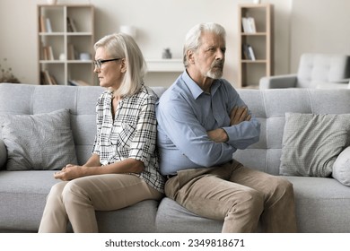 Annoyed ignoring senior couple sitting on home couch back to back, looking away, keeping silence after arguing, thinking on breakup, separation, relationship problems, conflict - Powered by Shutterstock