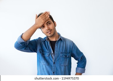 Annoyed Indian man slapping forehead and blaming himself. Regretful handsome dark haired man wearing denim shirt gesturing and looking at camera. Forgetfulness concept.