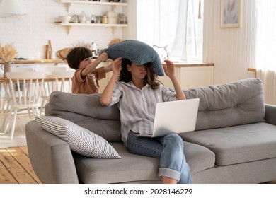 Annoyed Irritated Female Try To Work From Home With Hyperactive Preschool Kid. Naughty Small Child Hit Mother With Pillow. Mom And Son On Covid Quarantine. Freelance Occupation And Parent Lifestyle