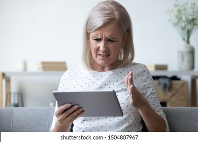 Annoyed Mature Woman Having Problem With Broken Or Discharged Computer Tablet, Angry Older Female Irritated By Spam Message Or Bad News, Looking At Electronic Device Screen Close Up