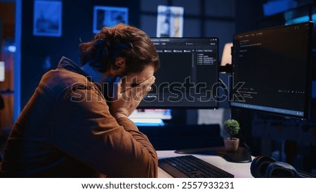 Annoyed software developer exasperated after failing to remove all bugs while coding on computer desktop. Teleworking IT specialist throwing keyboard, frustrated by script errors, camera B