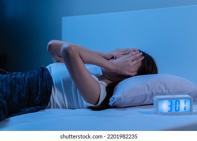 Annoyed, Stressed, asian young beautiful, pretty woman, girl suffering from insomnia, awake in bed at night, covering face with hand because of disturbed loud noise, unable sleep. Restless people. - Shutterstock ID 2201982235