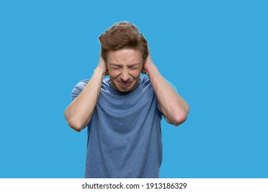 Annoyed Teen Boy Closing His Ears With Hands. American Boy With Clossed Eyes Isolated On Blue Background.