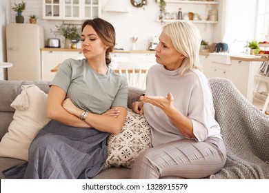 Annoyed Teen Girl Sitting On Sofa With Arms Crossed, Not Listening To Her Middle Aged Mother. 45 Year Old Woman Lecturing Her Stubborn Daughter. Relationship Problem, Age Gap And Different Generations