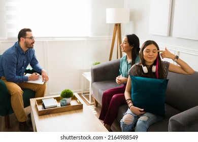 Annoyed Teenage Girl Putting A Finger In Her Head And Feeling Angry During A Family Therapy Session 