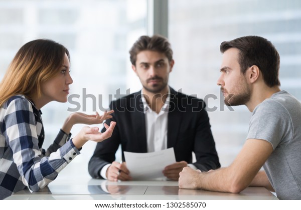 Annoyed unhappy married couple arguing in lawyers\
office get divorced, angry family spouses split up having\
disagreement disputing about breaking up and divorce settlement,\
legal separation\
concept