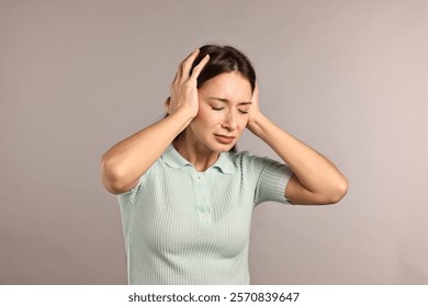 Mujer molesta que cubre sus oídos debido al sonido fuerte en el fondo gris claro