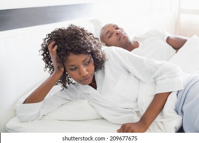 Annoyed woman lying in bed with boyfriend at home in the bedroom