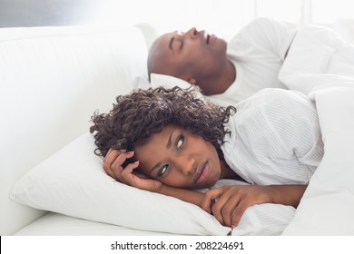Annoyed woman lying in bed with snoring boyfriend at home in the bedroom