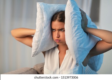 Annoyed Young Lady Covering Ears With Pillow Irritated Because Of Noise At Home. Bad Sound Insulation. - Powered by Shutterstock