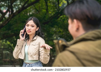 An annoyed young lady rebuffs a bothersome man while talking on her phone. An inappropriate approach