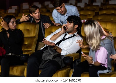 Annoying man talking on the mobile phone at the movie theater people in cinema is angry him - Powered by Shutterstock