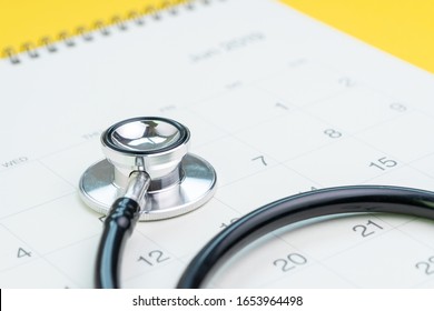 Annual Health Checkup, Medical Appointment Or Examination Schedule, Doctor Stethoscope On White Clean Calendar On Solid Yellow Background.