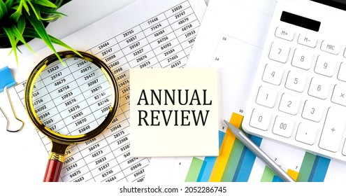ANNUAL REVIEW text on sticker on diagram with magnifier and calculator. Business - Shutterstock ID 2052286745