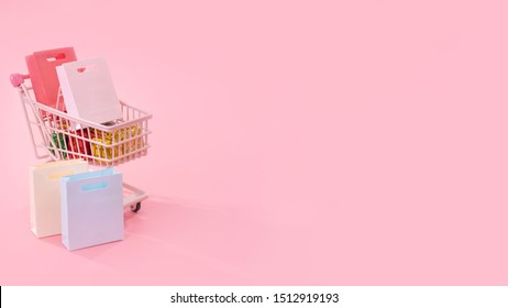 Annual sale shopping season concept - mini red shop cart trolley full of paper bag gift isolated on pale pink background, blank copy space, close up - Powered by Shutterstock