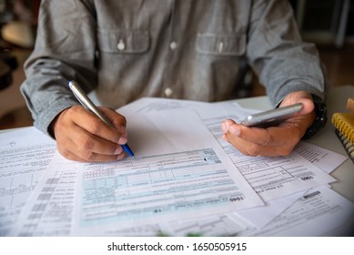 Annual tax form 2022 for individual income under US law at home office desk. Season to pay tax, Accountant calculate refund tax and using phone to work online and report dataTax.Budget plan concept. 