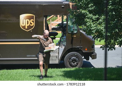 Anoka, MN/USA - July 24, 2020. An UPS delivery driver scans a package before leaving the order at a house.