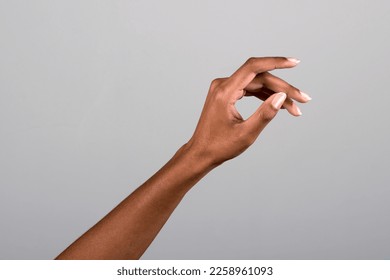 Anonymous African American female with long natural nails raising arm against gray background