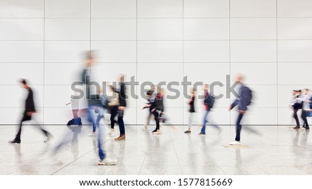 Anonymous blurred business people rush through trade fair hall or airport