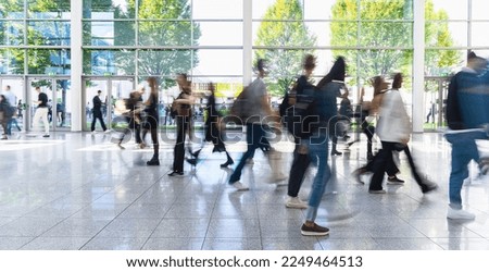 Anonymous blurred crowd of business people walks by gear on a trade fair or in an airport