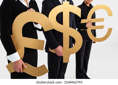 Anonymous Business People Team, Businessman And Businesswomen, Holding Large Gold Money Currency Symbols, British Pound, Dollar And Euro. Exchange Rate Or Globalisation Global Trade Concept.