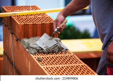 Anonymous Construction Worker On A Building Site When Building A House Built A Wall Of Brick. Brick Wall Of A Solid House. Symbolic Image For Illegal Work And Bungling