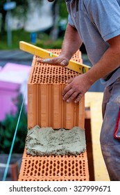 Anonymous Construction Worker On A Construction Site During Construction Erected A Wall Of Bricks. Brick Wall Of A Solid House. Symbol Picture For Illegal Work And Botch