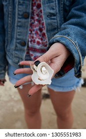 Anonymous crop of woman holding sea shell wearing denim jacket and denim shorts - Shutterstock ID 1305551983