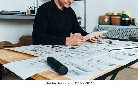 An Anonymous Designer Using Digital Tablet at Design Studio. 
Cropped unrecognizable furniture designer sketching drawing design using a pen, ruler and digital tablet while sitting at his office desk.