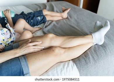 Anonymous Family Sharing Time In Bedroom. Legs Of Mom And Kids Resting On Bed Watching Tv. Nanny Taking Care Of Children Concept