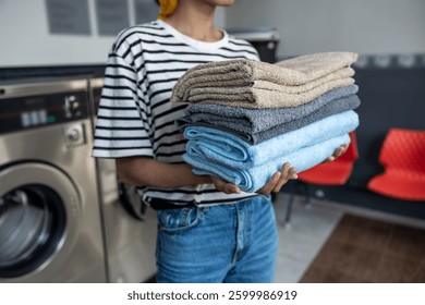 Anonymous female in self-service laundry using washing machine to clean her towels
