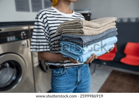 Anonymous female in self-service laundry using washing machine to clean her towels