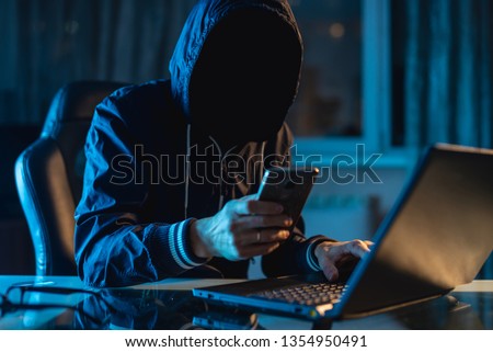 Anonymous hacker programmer uses a laptop to hack the system in the dark. Creation and infection of malicious virus. The concept of cybercrime and hacking database