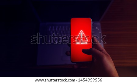 An anonymous hacker and uses a malware with mobile phone to hack password the personal data and money from Bank accounts. The concept of cyber crime.