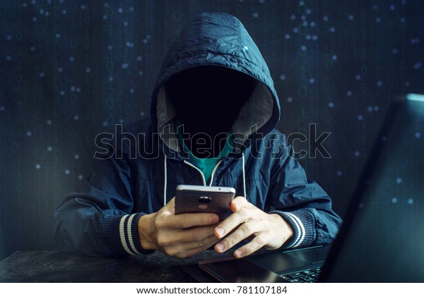 An\
anonymous hacker without a face uses a mobile phone to hack the\
system. Stealing personal data and money from Bank accounts. The\
concept of cyber crime and hacking electronic\
devices