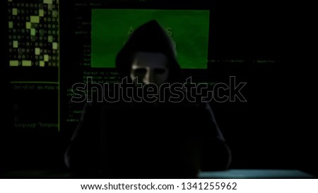 Anonymous in hoodie cracking codes on laptop, cyberterrorism, internet security