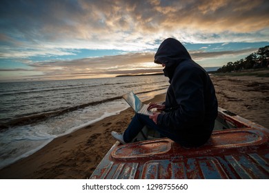 Anonymous in the internet. Single programmer or hacker working on the islands beach.