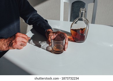 Anonymous Male With Glass Of Whiskey From Bottle While Sitting At Table And Drinking Alcohol At Home