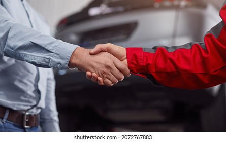 Anonymous Male Technician And Customer Shaking Hands Near Car After Coming To Agreement In Garage